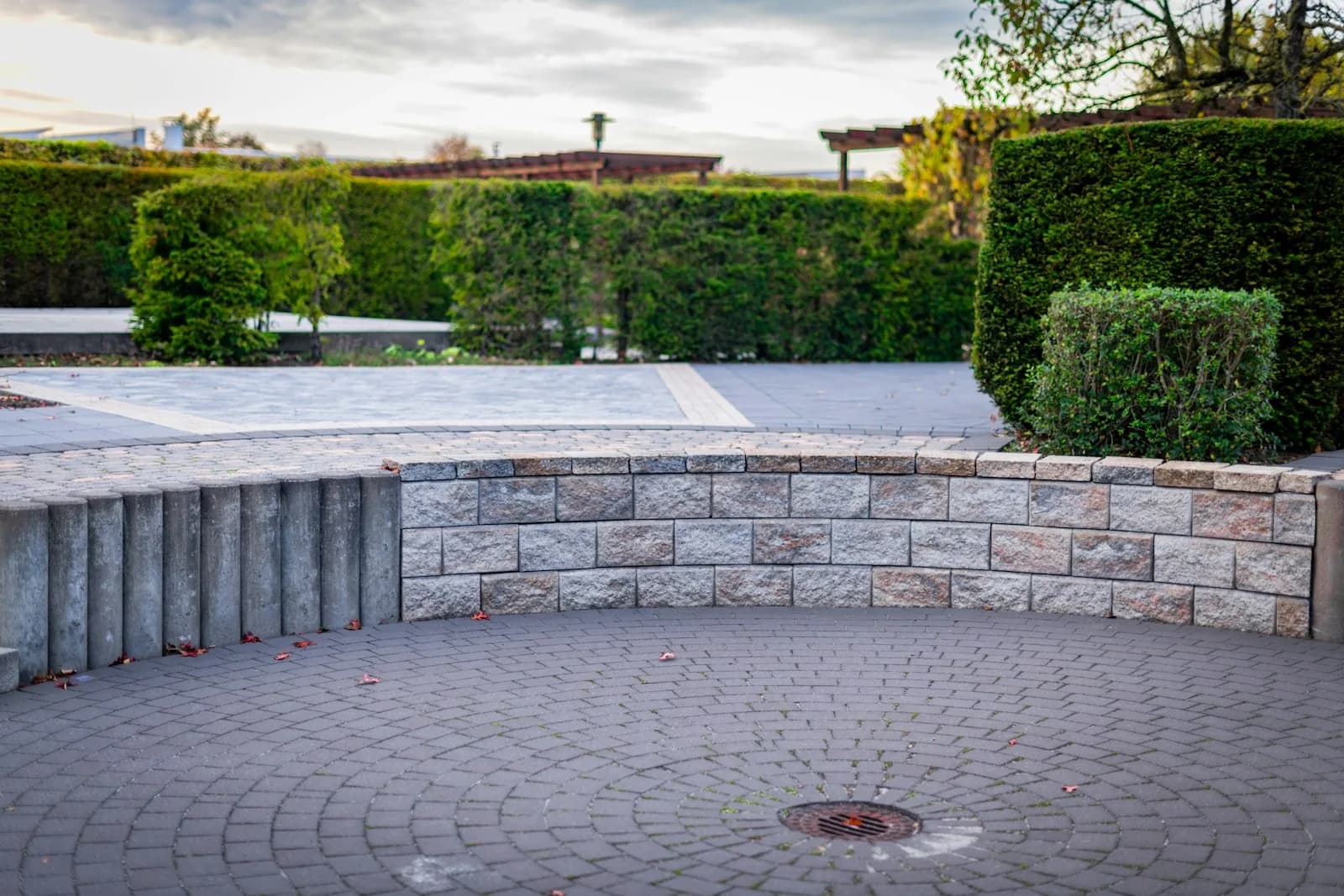 Geschwungene Natursteinmauer um eine gepflasterte Fläche